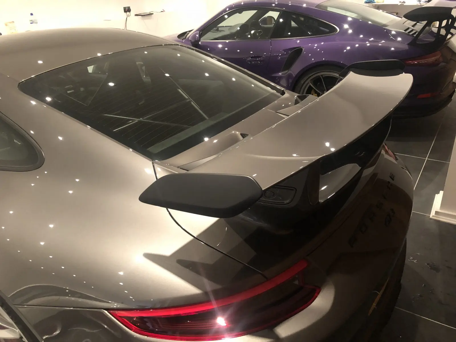 Grey Porsche 911 with a rear wing under studio lights