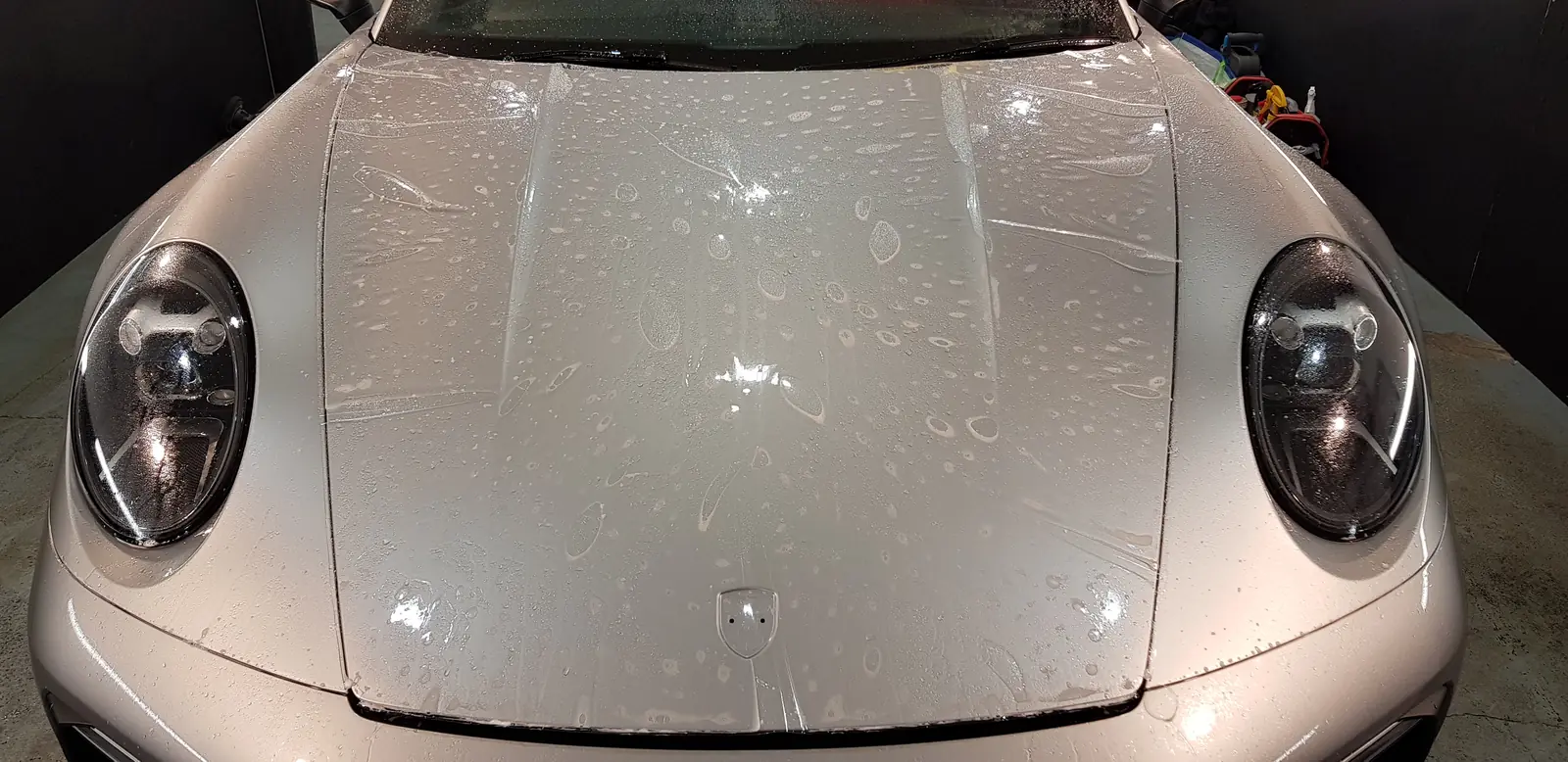 Paint protection film being fitted to the bonnet of a silver Porsche 911
